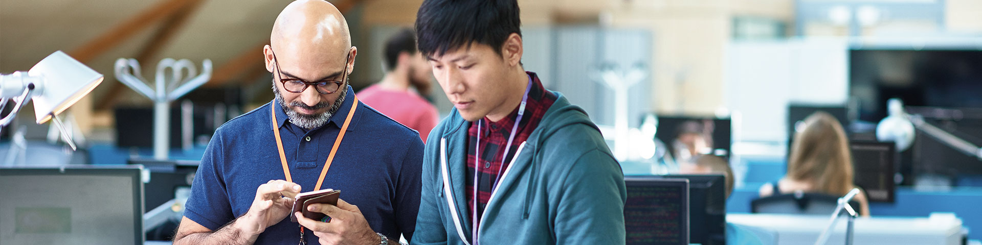 Two men in standing in office and working on their phones