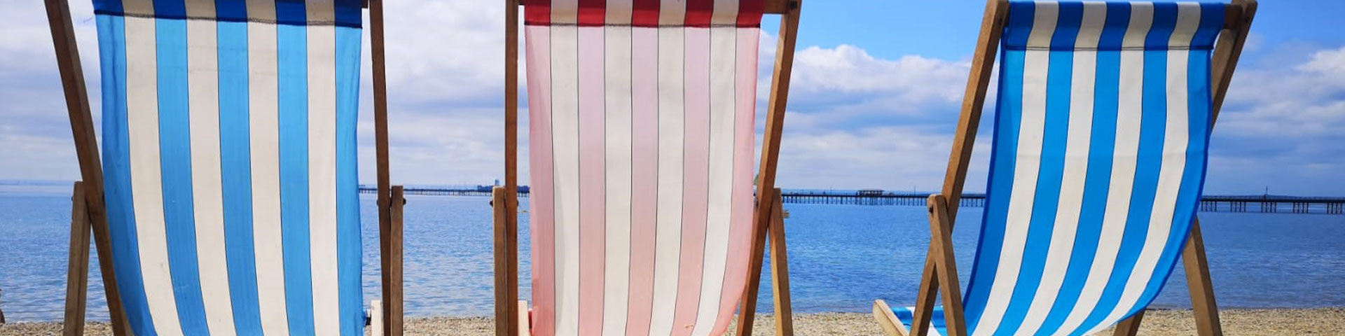Blue and red deckchairs in a line on a beach